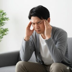 カフェインの離脱症状であるひどい頭痛に苦しむ日本人男性。